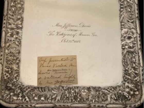 A silver tray with ornate floral edging and an engraved inscription for Mrs. Jefferson Davis from The Citizens of Macon, Ga. Oct 25th 1888, with a handwritten note on the tray.